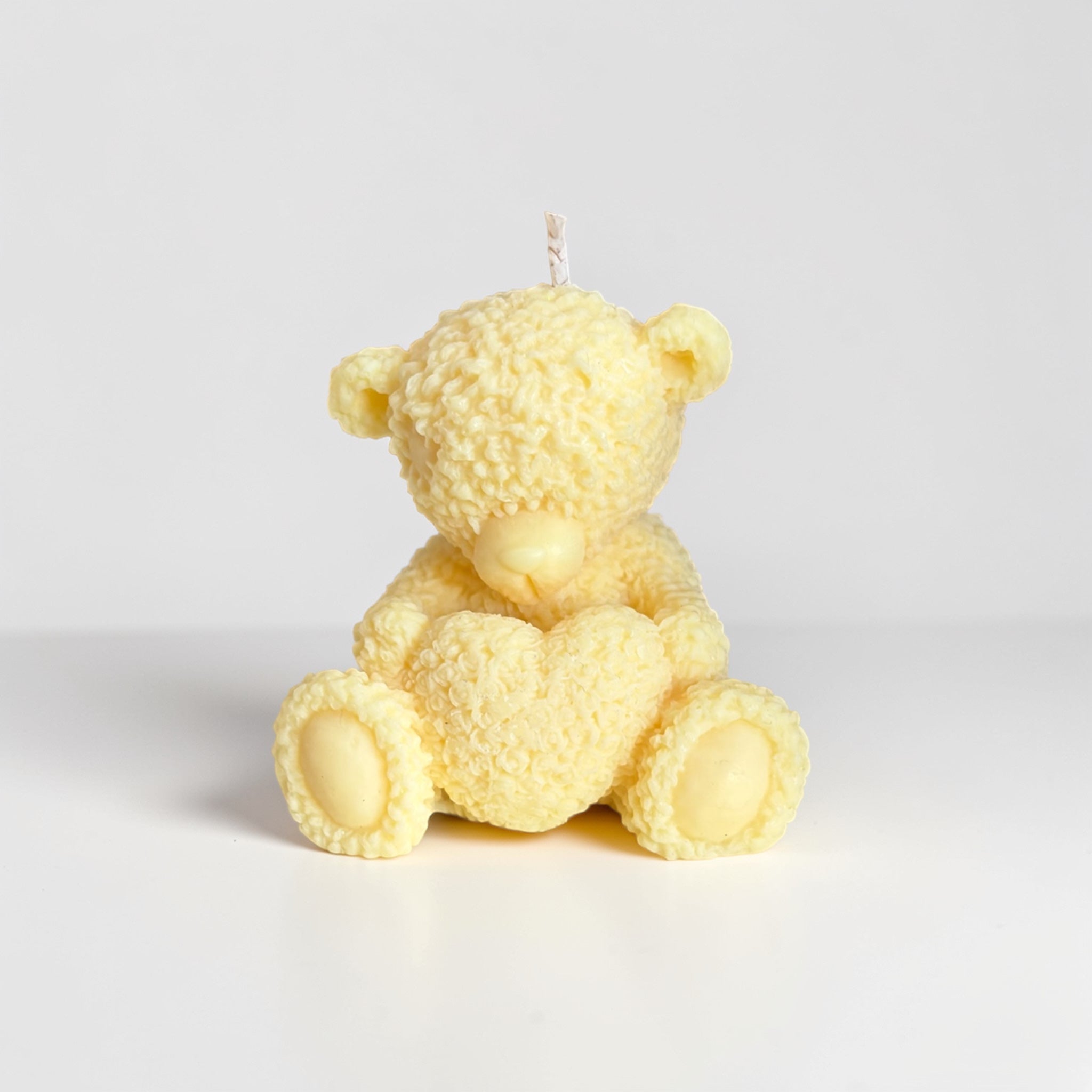 Teddy bear holding a heart decorative candle
