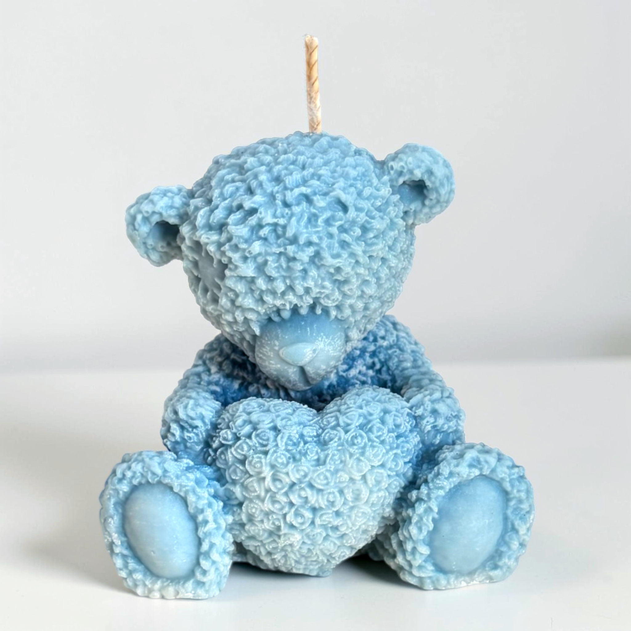 Teddy bear holding a heart decorative candle
