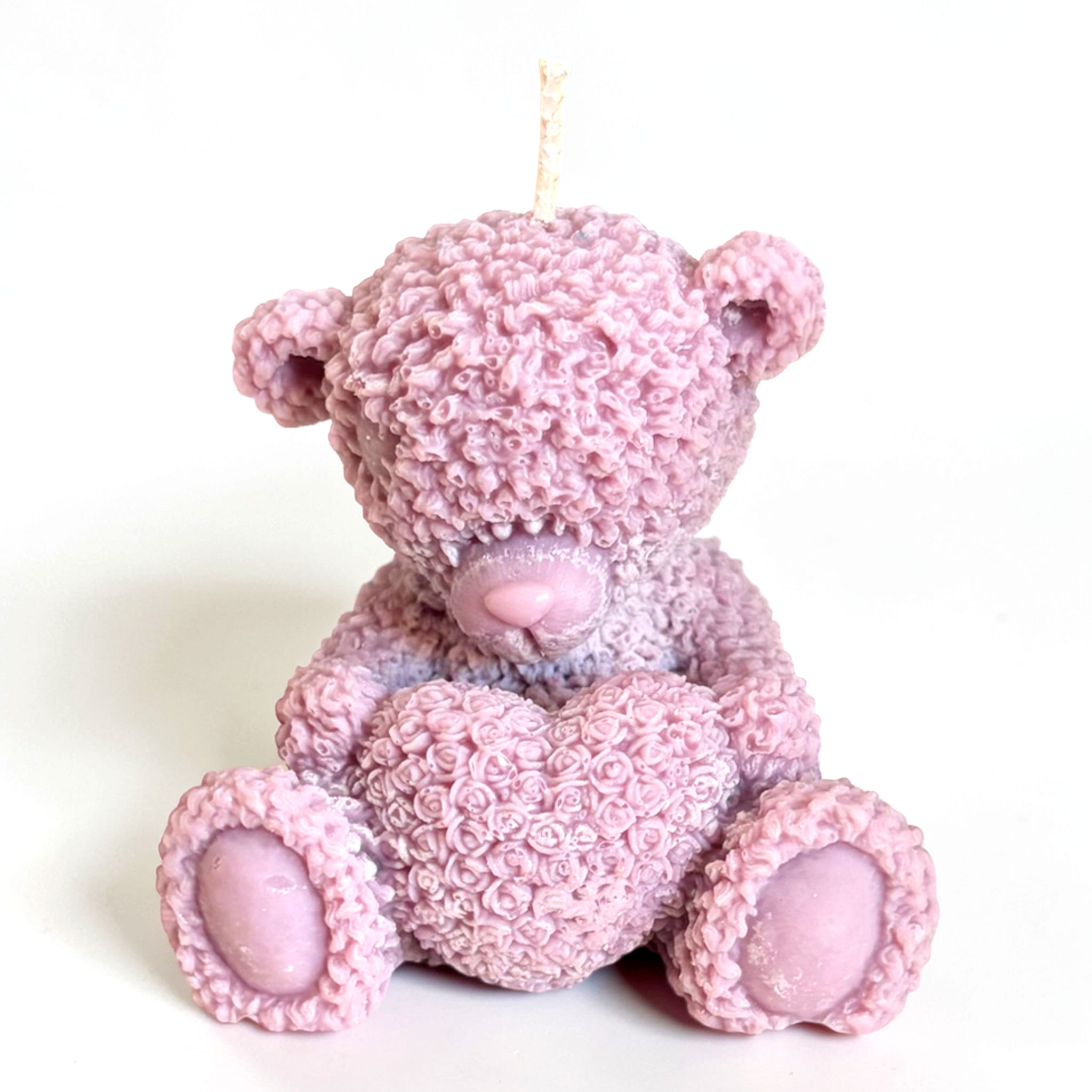Teddy bear holding a heart decorative candle