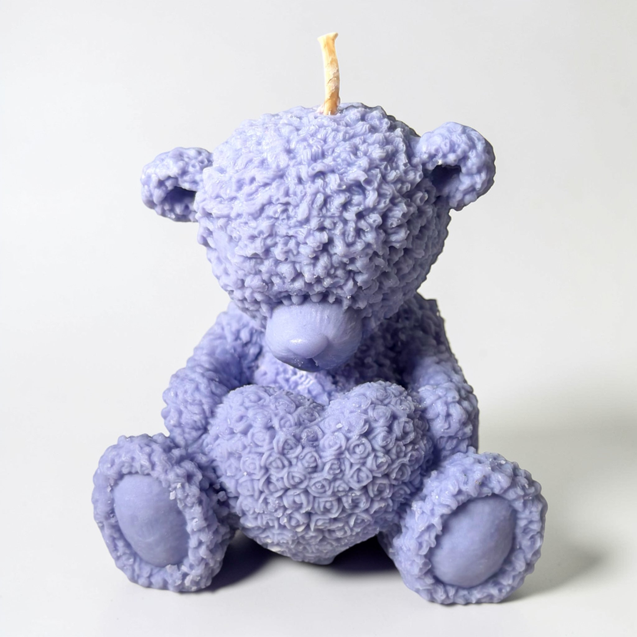 Teddy bear holding a heart decorative candle