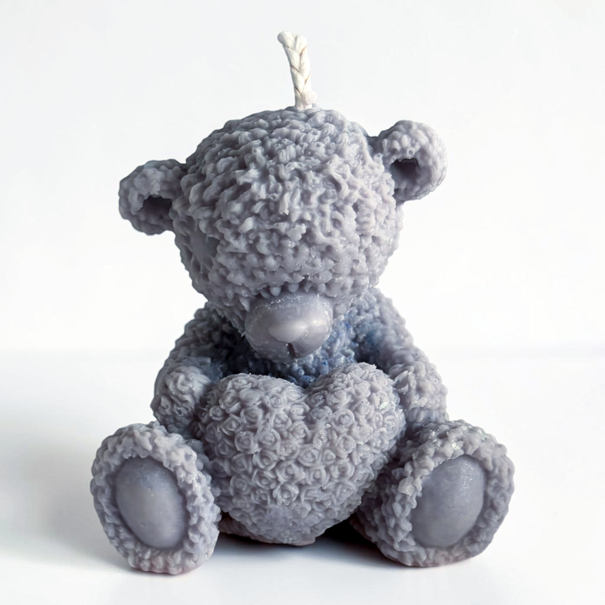 Teddy bear holding a heart decorative candle