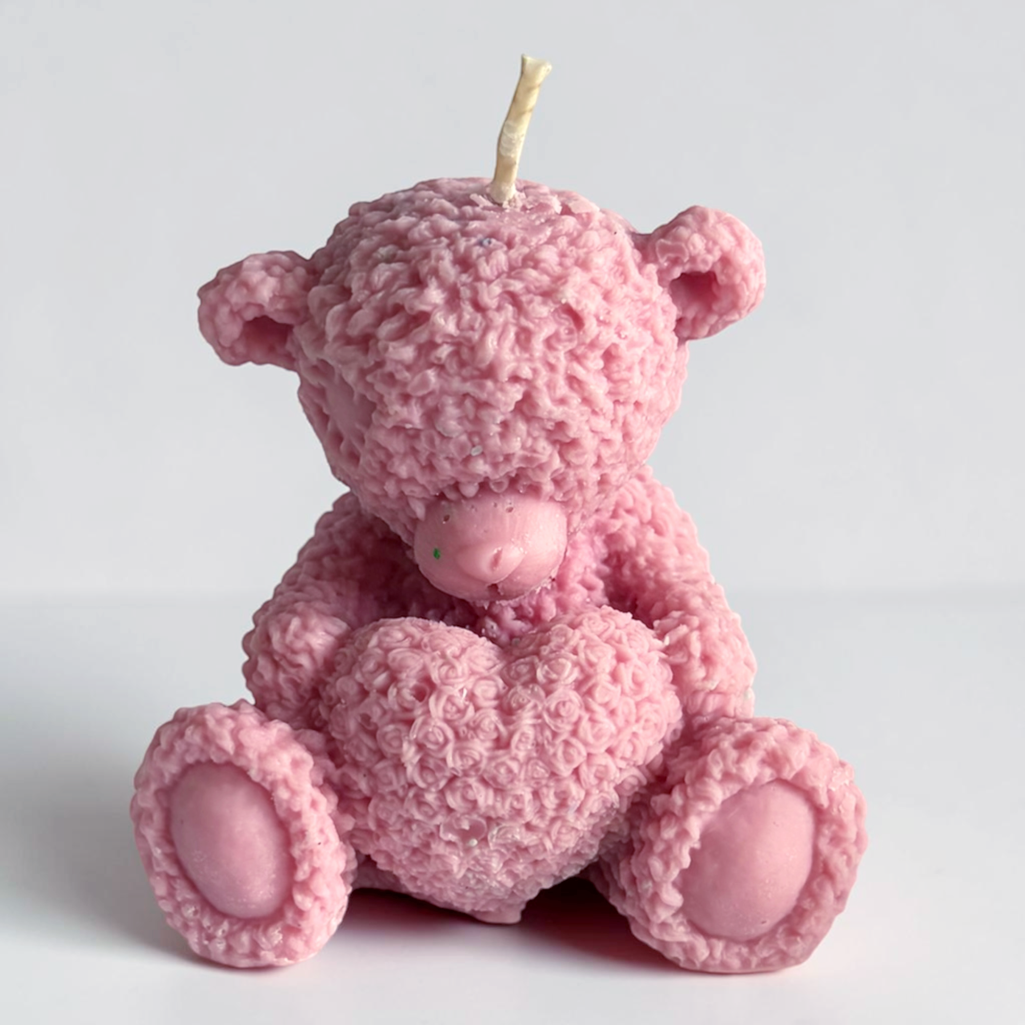 Teddy bear holding a heart decorative candle